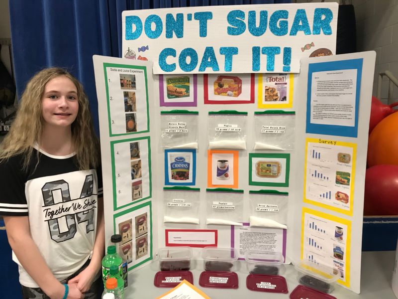 5th grader posing with her science fair project